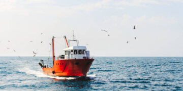 a blue cutter with a flock of seagulls on the North Sea in the sun with wind generators in the background. High quality photo