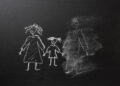 Chalk drawing of a child and parents on a blackboard, divorce trauma concept