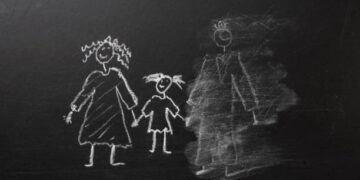 Chalk drawing of a child and parents on a blackboard, divorce trauma concept